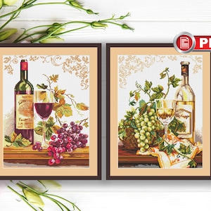 May include: Two framed cross-stitch embroidery designs featuring bottles of wine, glasses, and grapes. The left design features a red wine bottle and glass with red grapes. The right design features a white wine bottle and glass with green grapes.