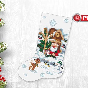 May include: A white Christmas stocking with a red and white Santa Claus, a reindeer, and a snowman in front of a wooden house with a clock. The stocking is decorated with snowflakes.