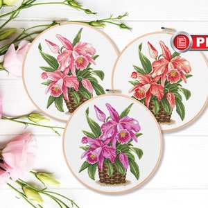 Può includere: Tre motivi da ricamo in telaio che rappresentano orchidee rosa, rosse e viola in un cesto intrecciato. I motivi sono pronti per essere ricamati.