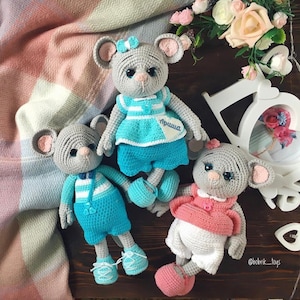 Könnte beinhalten: Drei gehäkelte Mäuse-Spielzeuge. Die Maus links trägt eine blaue Latzhose und ein weiß-blau gestreiftes Hemd. Die Maus in der Mitte trägt ein blaues Kleid mit weißen Streifen und ein weißes Etikett mit der Aufschrift "пришла". Die Maus rechts trägt ein rosa Hemd und eine weiße Hose.