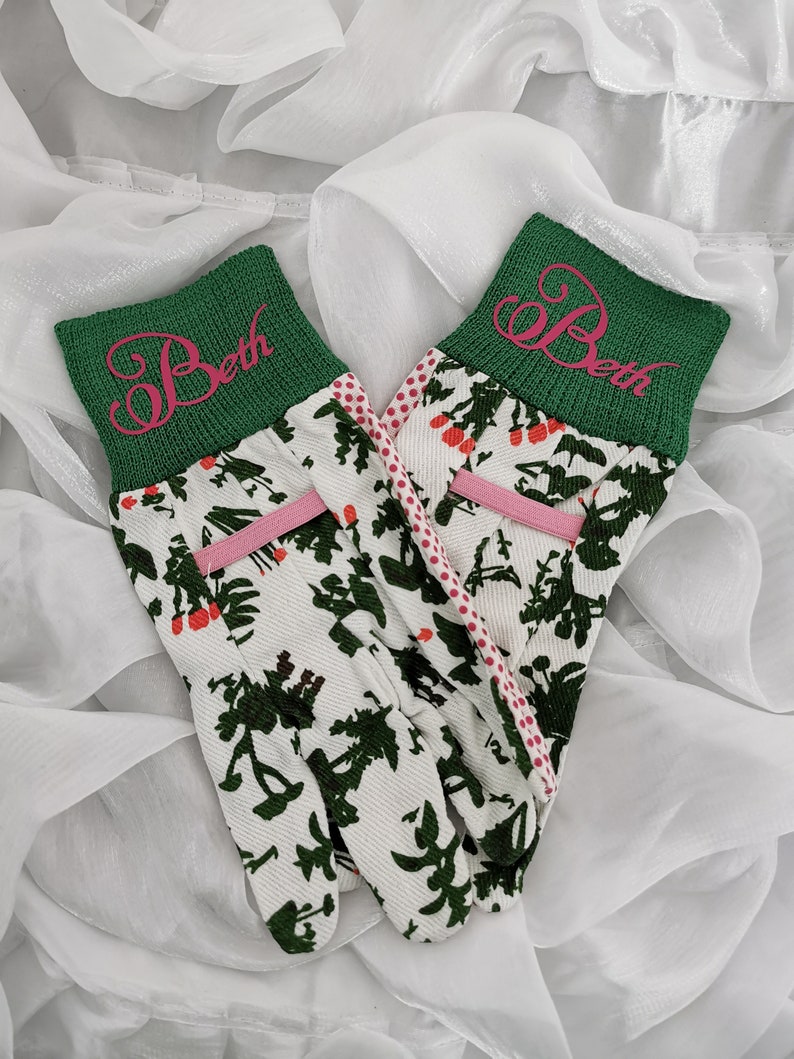 Peut inclure: Une paire de gants de jardinage blancs avec un poignet vert et des pois roses. Les poignets sont brod&eacute;s du nom "Beth" en rose.