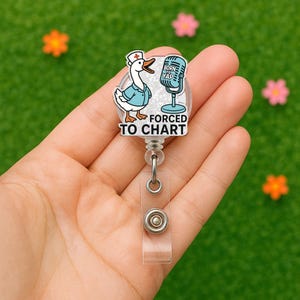 Op de afbeelding: Een witte glitter badgehouder met een cartoon gans die een verpleegstersmuts draagt en een microfoon vasthoudt. De tekst op de badgehouder luidt "Born to Yap, Forced to Chart".