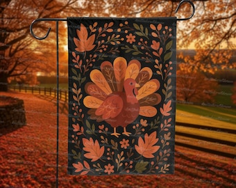 May include: A black garden flag featuring a turkey with a fanned tail, surrounded by fall leaves and floral elements. The turkey is brown and orange, with a red wattle. The leaves are in shades of orange and brown, creating a festive autumn theme.