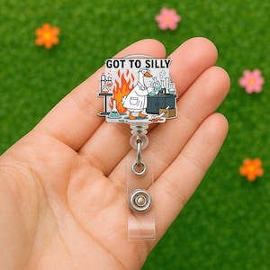 May include: A white goose wearing a lab coat and goggles is holding a beaker and standing in front of a fire. The text "GOT TO SILLY" is above the goose. The image is on a clear plastic retractable badge holder.