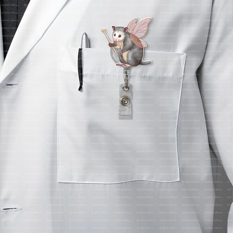 May include: A whimsical opossum badge reel with pink fairy wings and a golden wand. The opossum is gray and white, attached to a clear plastic reel with a metal clip. The badge reel is clipped to a white lab coat pocket.