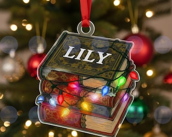 May include: A Christmas ornament shaped like a stack of books with the name "LILY" on the top book. The books are decorated with colorful Christmas lights and a red ribbon for hanging. The books have a vintage look.