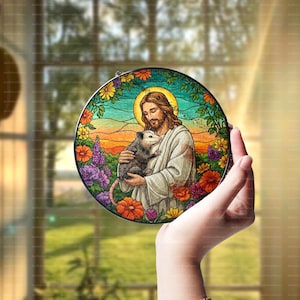 May include: A stained glass round ornament featuring a man with long hair and beard holding a small opossum. The man is wearing a long robe and the opossum is brown and white. The background is a colorful floral design.