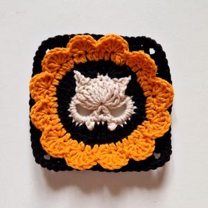 This crochet granny square features a classic Halloween color palette, 12 orange petals surrounding a cream cat skull motif on black background. The rich orange petals pop against the black square frame, making it perfect for Halloween bunting, table runners, or spooky blankets. For crafters who love alternative designs, punk or goth crochet aesthetics, or want to add a unique twist to their Halloween handmade creations.