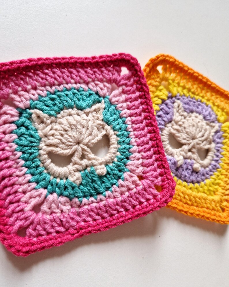 Peut inclure: Deux carr&eacute;s crochet&eacute;s avec des motifs de cr&acirc;ne. L'un pr&eacute;sente une palette de rose, turquoise et cr&egrave;me, l'autre jaune, violet et cr&egrave;me. Les carr&eacute;s sont faits &agrave; la main et ont un aspect textur&eacute;.