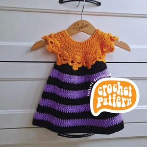 Peut inclure: Robe crochetée à rayures orange, noires et violettes, suspendue à un cintre en bois. La robe présente une encolure festonnée orange. Une bulle orange indique "crochet pattern".