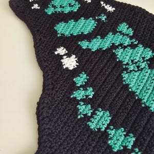 Close up tapestry crochet chart motif, malachite butterfly design in teal and black, crochet pattern detail