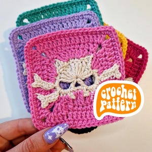 May include: Crocheted square coasters in shades of pink, purple, green, yellow, and red. The pink coaster features a skull and crossbones design. The image includes a sticker that says "crochet pattern".