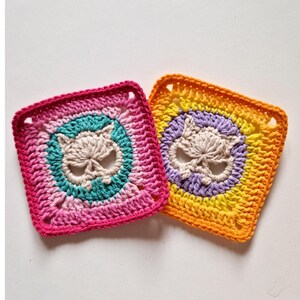 Peut inclure: Deux carr&eacute;s crochet&eacute;s avec un motif de cr&acirc;ne. L'un pr&eacute;sente une palette de couleurs rose, turquoise et cr&egrave;me, tandis que l'autre est orange, jaune, violet et cr&egrave;me. Les carr&eacute;s sont faits &agrave; la main et ont un aspect textur&eacute;.