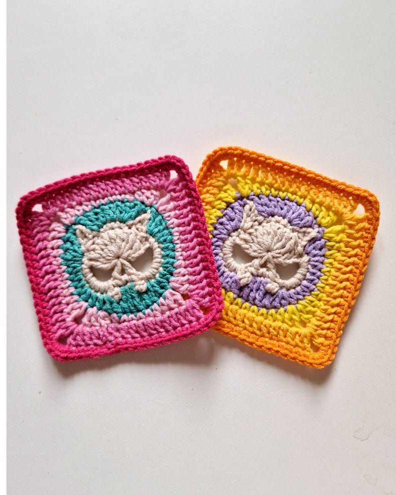 Peut inclure: Deux carr&eacute;s crochet&eacute;s avec un motif de cr&acirc;ne. L'un pr&eacute;sente une palette de couleurs rose, turquoise et cr&egrave;me, tandis que l'autre est orange, jaune, violet et cr&egrave;me. Les carr&eacute;s sont faits &agrave; la main et ont un aspect textur&eacute;.