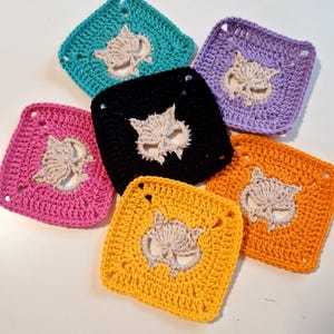 May include: A collection of six crocheted squares in various colors: teal, purple, black, orange, yellow, and pink. Each square features a cream-colored owl design in the center. The squares are arranged in a circular pattern.