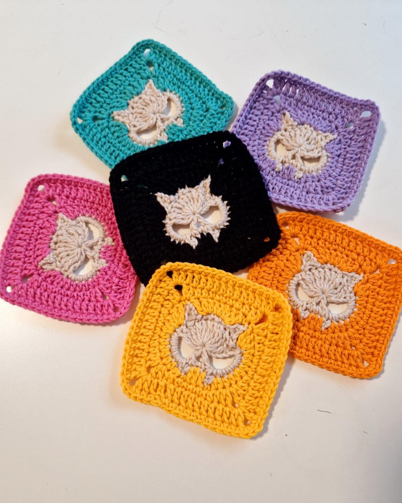 May include: A collection of six crocheted squares in various colors: teal, purple, black, orange, yellow, and pink. Each square features a cream-colored owl design in the center. The squares are arranged in a circular pattern.