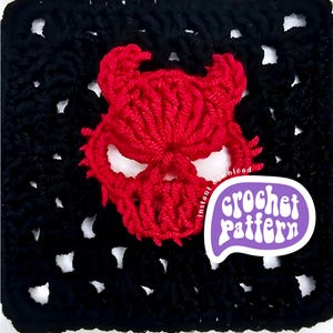 Puede incluir: Un cuadrado de ganchillo negro con un diseño de calavera de diablo rojo. La calavera tiene cuernos y cuencas de los ojos. Una burbuja de diálogo púrpura con "crochet pattern" está en la esquina inferior derecha.