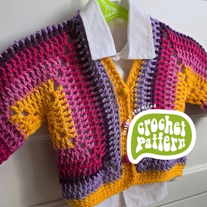 Puede incluir: Un cárdigan de ganchillo colorido en tonos amarillos, rosas y morados, con una camisa blanca con cuello debajo. El cárdigan está colgado de una percha verde. La imagen incluye el texto "crochet pattern".