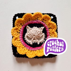 May include: A square crochet pattern featuring a central skull design in beige, surrounded by a black circle and a pink ring. The outer layer is a yellow scalloped edge, set against a black square. The text "crochet pattern" is in a purple speech bubble.