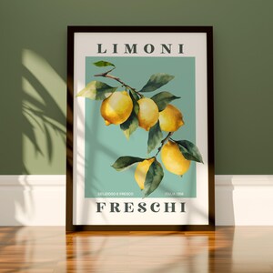 May include: Framed art print featuring a watercolor illustration of lemons on a branch with green leaves. The print has the word "LIMONI" at the top and "FRESCHI" at the bottom, with Italian text in between. The background is a light teal color.