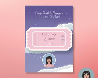 May include: A die-cut sticker with a pastel purple and pink design. The sticker features a ticket shape with the text "The cozy gamer club." The background is a gradient of purple and blue with clouds and stars. The sticker also includes the text "Em's Pastel Designs."