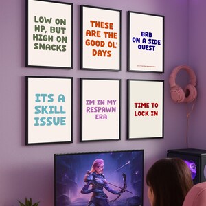 Peut inclure: Une configuration de jeu avec un écran d'ordinateur affichant un personnage fantastique, un clavier et une chaise de jeu rose. Six affiches encadrées avec des phrases de jeu sont accrochées au mur, dont "Low on HP, but high on snacks."