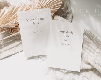 Puede incluir: Dos tarjetas blancas con el texto "Your design here" y "5x7 PSD + JPG" sobre un fondo blanco con una tela beige y hojas de palma secas.