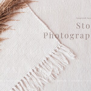 May include: A cream-coloured, textured rug with a fringed edge and a bundle of dried pampas grass. The words "Stock Photography" are displayed on the rug. The image has a soft, natural aesthetic.