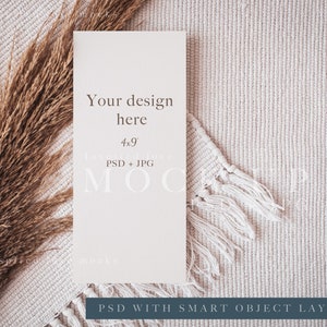 May include: A white card mockup with the text "Your design here 4x9 PSD + JPG MOO" on a beige textured surface with a dried grass sprig and a white tassel.