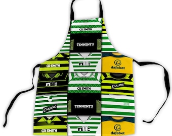 Puede incluir: Un delantal a rayas verdes y blancas con lazos negros. Presenta un collage de camisetas de fútbol con logotipos de patrocinadores como "CR SMITH", "TENNENT'S", "ntl:" y "CARLING". El delantal tiene una correa negra para el cuello.