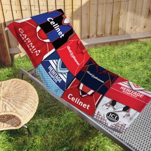 May include: A beach towel featuring a patchwork design of vintage sports jerseys with logos like Cellnet, dial a phone, and Heritage Hampers. The towel is red, blue, white, and black.