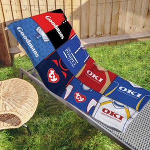 May include: A beach towel featuring a collage of vintage sports jerseys and logos, including "Goodmans", "The Pompey Centre", and "OKI Printing Solutions". The towel is blue, red, white, and yellow.