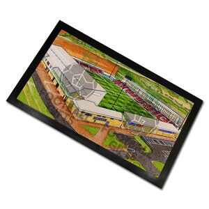 May include: A rectangular doormat with a black border displays a watercolour illustration of a sports stadium. The stadium has a green pitch, red seating, and buildings with yellow and grey roofs. The image is a detailed, artistic representation.