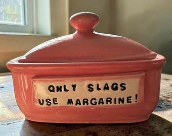 A gorgeous handmade, hand-painted pink ceramic butter dish with a very important message: ‘Only slags use margarine.’”!