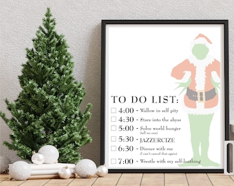 Puede incluir: Un cuadro enmarcado con una ilustración de un personaje similar al Grinch y una "TO DO LIST" humorística. La lista incluye tareas como "Wallow in self pity" y "Solve world hunger". Un pequeño árbol de Navidad y adornos están en primer plano.