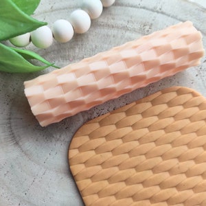 Op de afbeelding: Twee roze siliconen deegrollers met een geweven patroon. De deegrollers worden gebruikt om decoratieve patronen op fondant of deeg te maken.