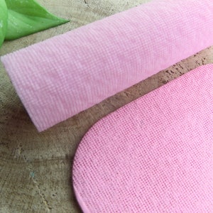 Op de afbeelding: Twee roze microvezeldoeken, een opgerold en een plat. De doeken zijn zacht en textuur.