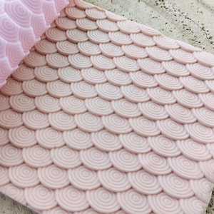 Könnte beinhalten: Ein rosafarbener Silikon-Nudelholz mit einem kreisförmigen Muster, perfekt zum Erstellen von dekorativen Mustern auf Fondant oder Teig.