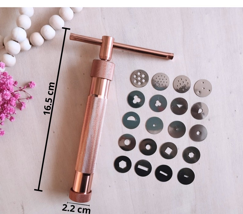 Peut inclure: Une presse &agrave; biscuits en or rose de 16,5 cm de haut et 2,2 cm de diam&egrave;tre. La presse est livr&eacute;e avec 16 moules &agrave; biscuits interchangeables diff&eacute;rents.
