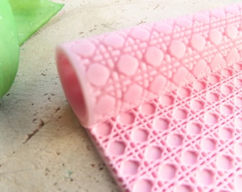 May include: Pink silicone baking mat with a raised geometric pattern. The mat is rolled up, showing the pattern on both sides.