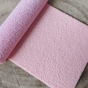 Può includere: Un primo piano di un tessuto rosa testurizzato. Il tessuto ha una texture morbida e soffice ed è perfetto per progetti di artigianato.