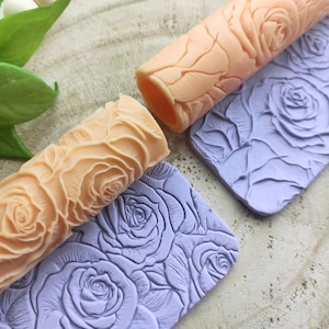 Peut inclure: Deux rouleaux à pâtisserie avec des motifs de roses. L'un est de couleur orange clair et l'autre de couleur violet clair. Les deux sont en silicone.