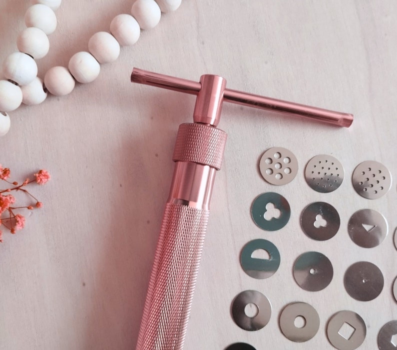 Peut inclure: Presse &agrave; biscuits en m&eacute;tal rose gold avec une poign&eacute;e en forme de T et une vari&eacute;t&eacute; d'emporte-pi&egrave;ces interchangeables. Les emporte-pi&egrave;ces comprennent une vari&eacute;t&eacute; de formes, notamment une fleur, une &eacute;toile, un cercle et un c&oelig;ur.