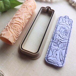 Op de afbeelding: Een set van drie polymer clay mallen voor het maken van ambachten. De mallen zijn in de vorm van een rechthoek, een deegroller en een label. De mallen hebben een rozenpatroon.
