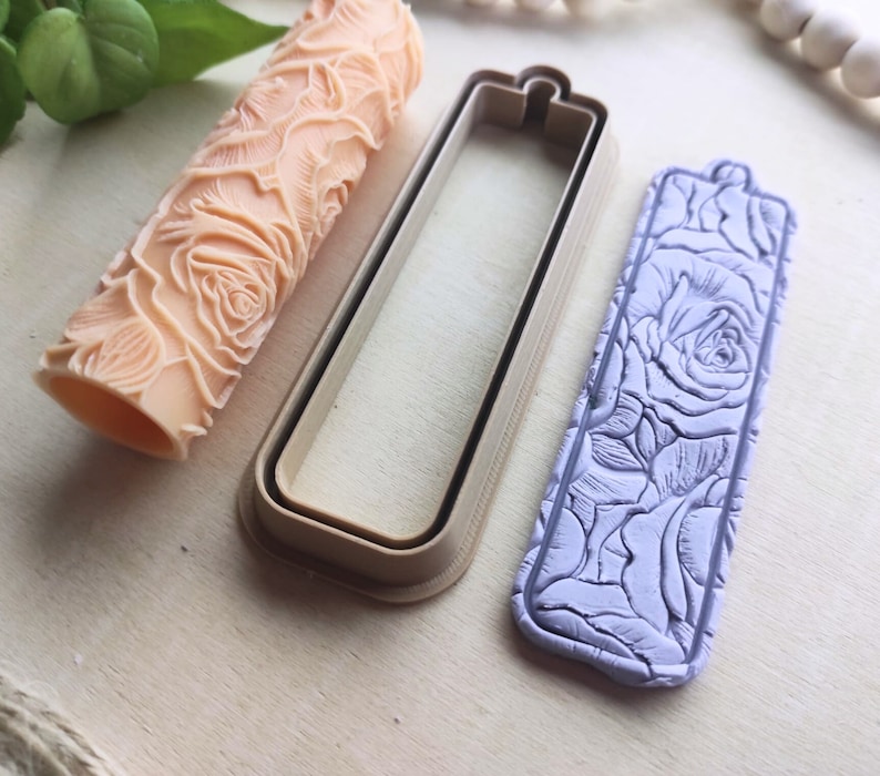 Op de afbeelding: Een set van drie polymer clay mallen voor het maken van ambachten. De mallen zijn in de vorm van een rechthoek, een deegroller en een label. De mallen hebben een rozenpatroon.