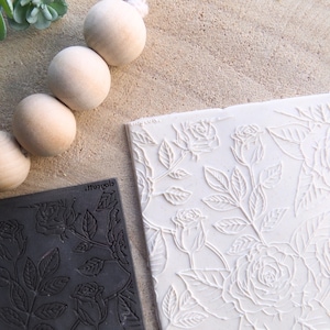 Pode incluir: Dois rolos de silicone com um padrão de rosas. Um é preto e o outro é branco.