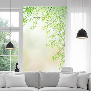Könnte beinhalten: Helle Innenansicht mit einem großen Fenster, das ein Wandbild aus grünen Blättern und Ästen zeigt. Der Raum verfügt über ein graues Sofa mit weißen Kissen, schwarze Pendelleuchten und weiße Vorhänge, was eine ruhige Atmosphäre schafft.