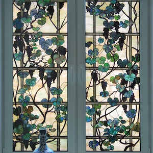 May include: A pair of double French doors with stained glass panels depicting a vine with green leaves and purple grapes. A blue and white porcelain vase sits on the windowsill below the doors.