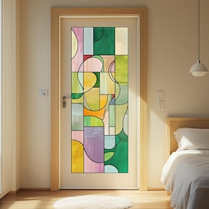 May include: A white door with a stained glass window featuring an abstract design. The window is composed of various shapes and colors, including green, yellow, pink, and purple. The door is set in a light wood frame.