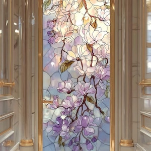 Könnte beinhalten: Ein dekoratives Buntglasfenster mit floralem Design. Es zeigt weiße und lila Magnolienblüten vor einem hellblauen und lavendelfarbenen Hintergrund, umrahmt von einem goldenen Rahmen. Ein dekoratives Element.